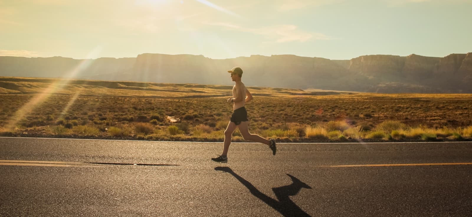 Man running along an open road at golden hour